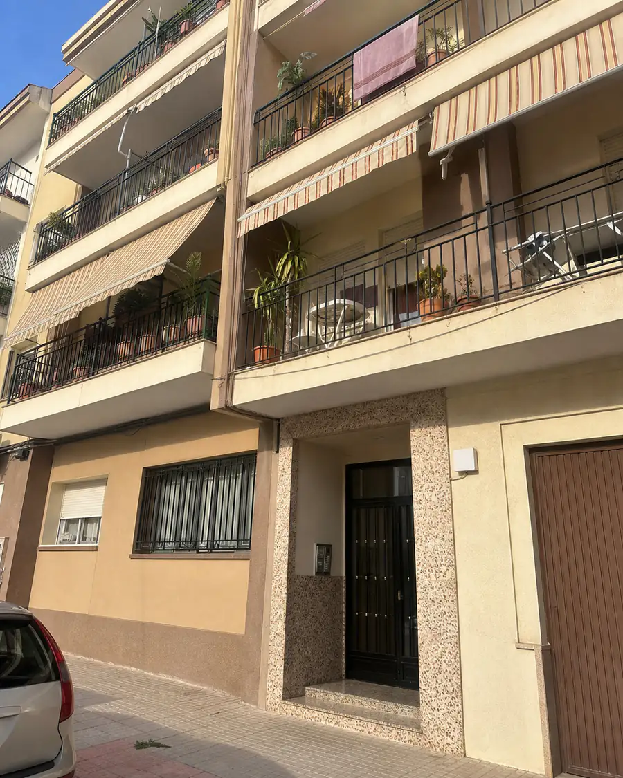 A Spanish apartment block with striped awnings and plants on the balconies