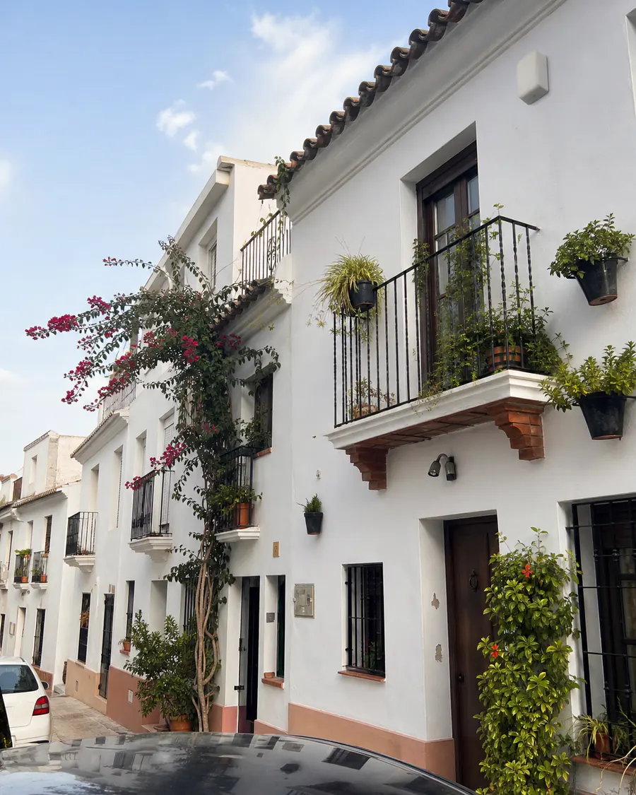 A street of whitewashed Spanish townhouses with balconies and flowering bougainvillea