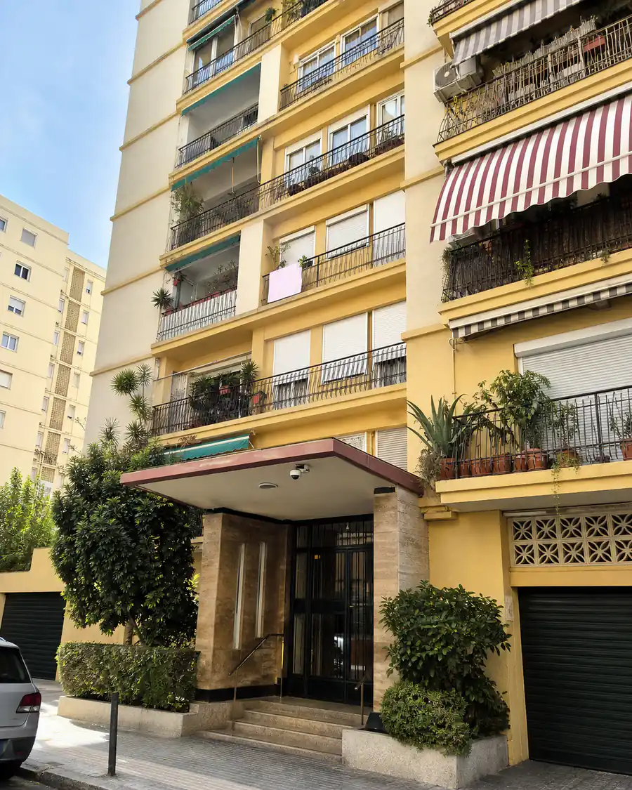 An urban Spanish apartment block from street level, with a camera under the entrance canopy