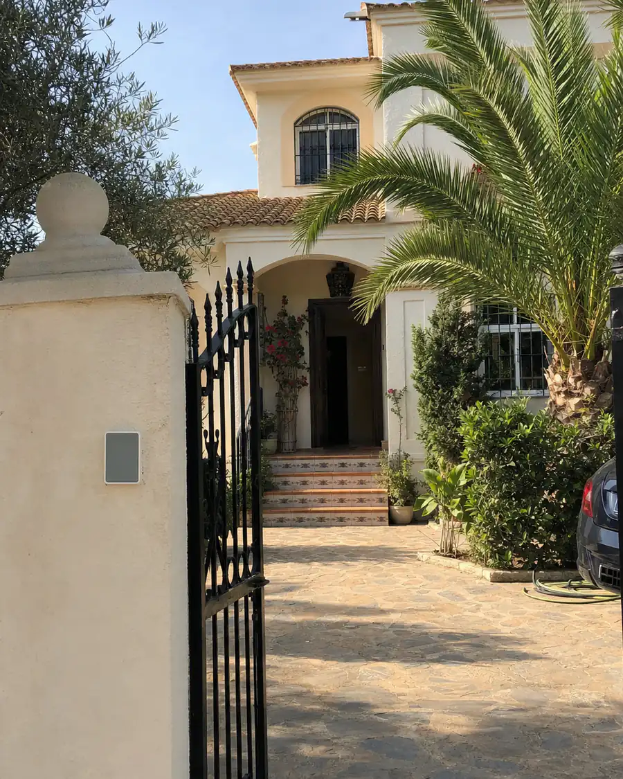 The gated entrance of a modern Spanish house, with an entry panel beside the door