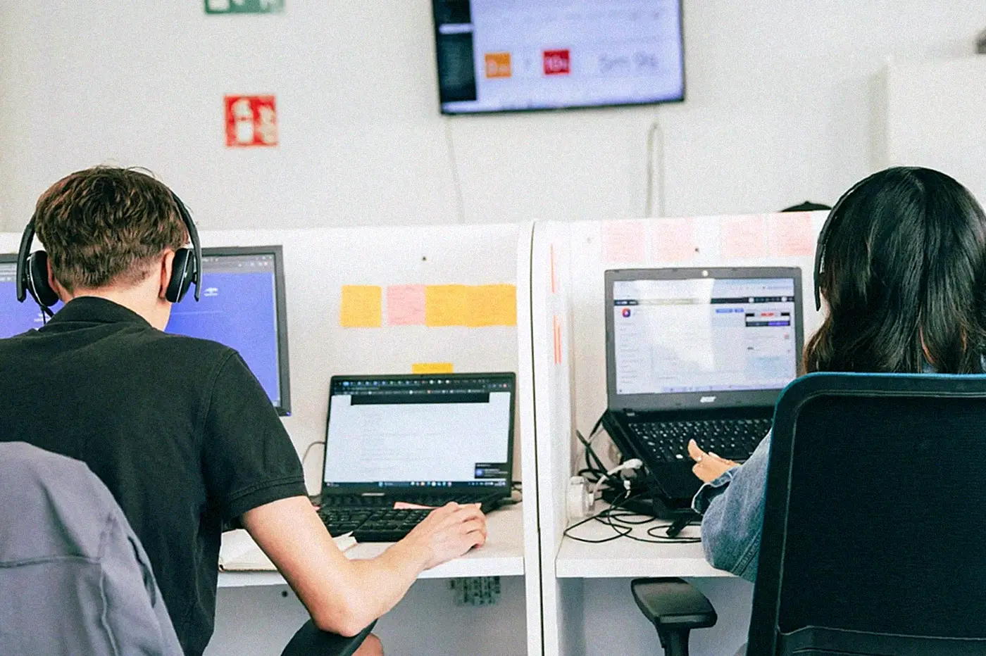 Two Selectra team members wearing headsets at their desks, seen from behind