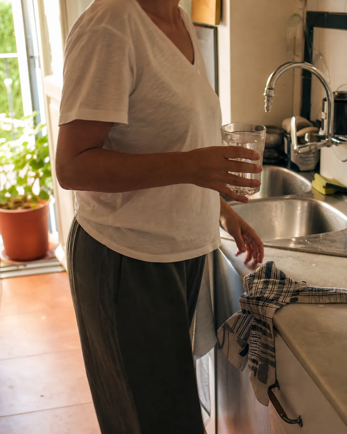 A woman filling a glass of tap water at the sink in a Sevillano kitchen
