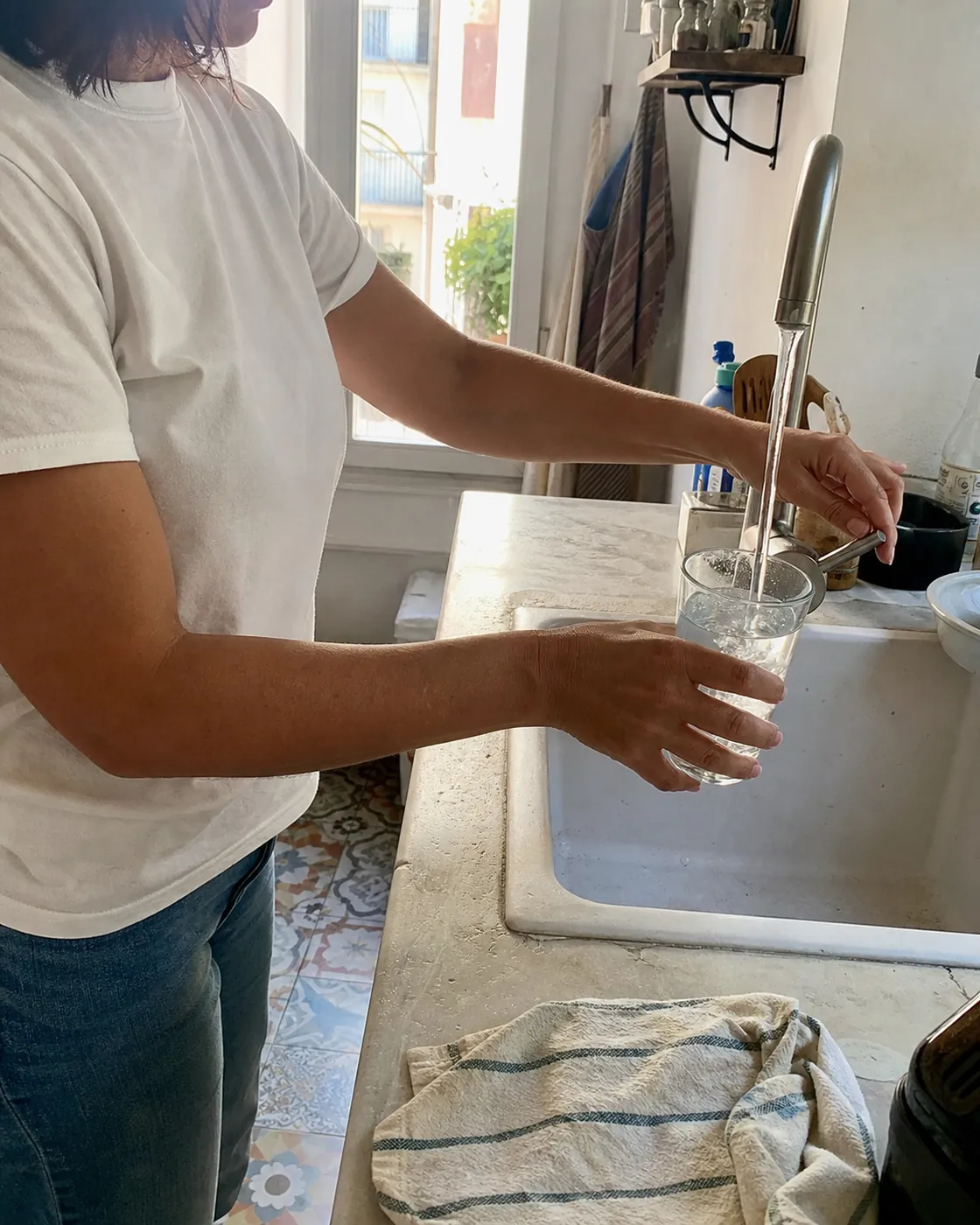 A man filling a glass of water at the kitchen tap in a Spanish home